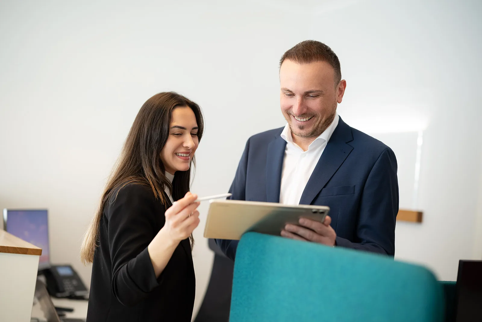 Beraterin und Kunde besprechen die Baufinanzierung am Tablet